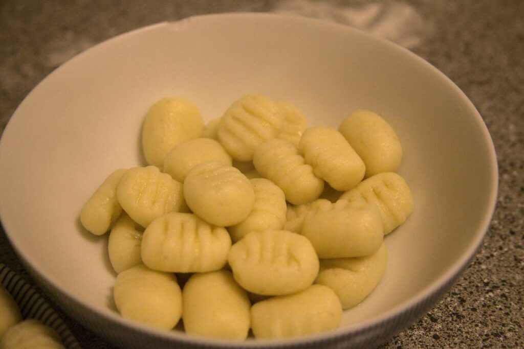 a white bowl with a serving of plain cooked gnocchi.