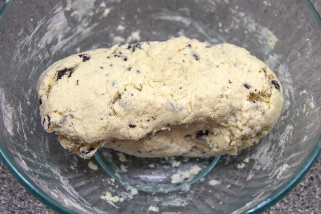 A lump of dough sits in a glass bowl. The dough is one solid mass and looks cohesive but slightly sticky.