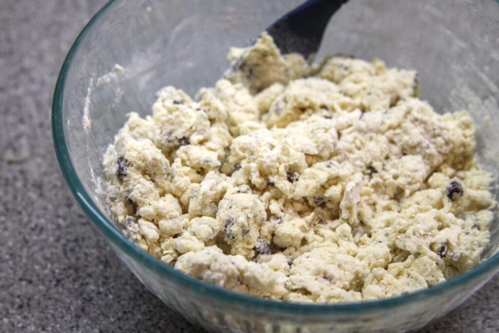 A close-up of a bowl containing scone dough. The dough looks clumpy and dry.