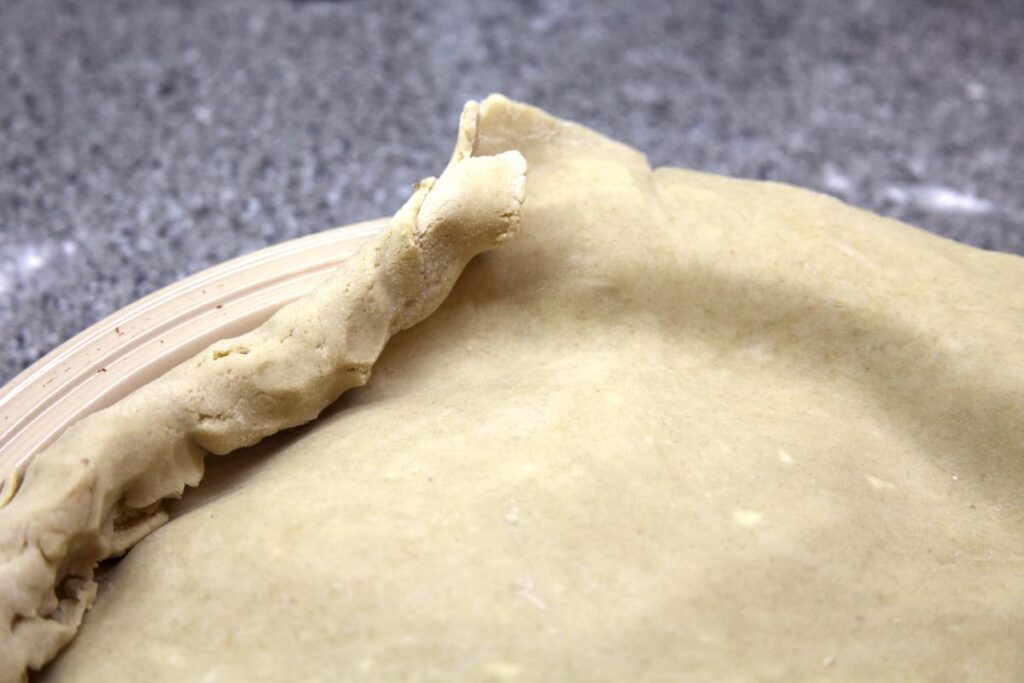 A close-up of the edge of a pie with the edge of the crust partially rolled up.